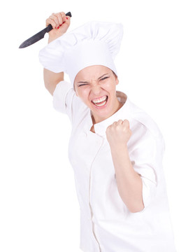 憤怒的女廚師在白色制服和帽子保持刀