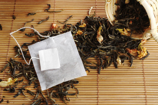 袋泡茶空白標(biāo)簽失去綠茶干茉莉花和一個(gè)木制的茶濾器（選擇性聚焦；對(duì)袋泡茶和標(biāo)簽的重點(diǎn)）