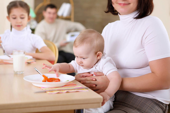 一個(gè)年輕的母親在家里喂她的嬰兒