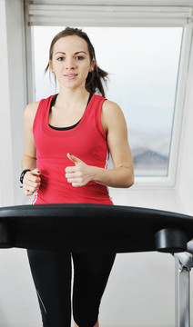 在健身俱樂部womanworkout在軌道上運行的機器