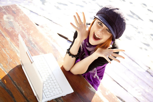 在海灘上與筆記本電腦的紅頭發(fā)女孩肖像。