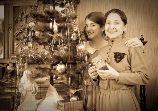 舊貨照片的女兒與母親裝飾圣誕樹在家里
