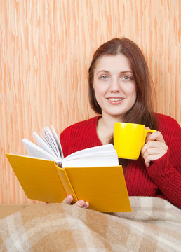 漂亮的年輕女孩在沙發(fā)上看書
