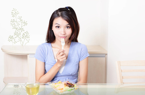 幸福的微笑的女人在家里沙拉