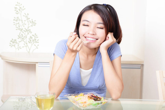 幸福的微笑的女人在家里沙拉