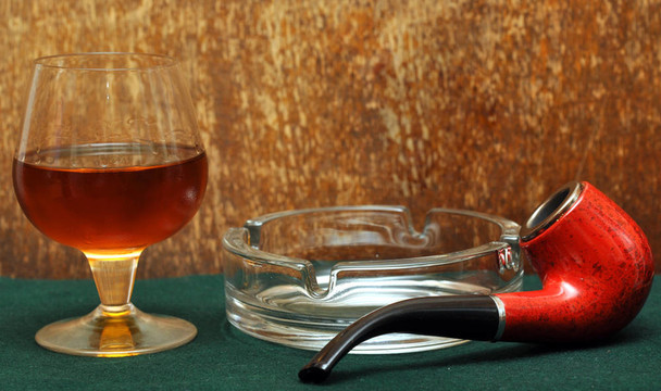 煙斗和一杯酒精在綠色毛氈