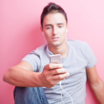 年輕英俊的男人在他的便攜式MP3播放器在自己的房間里聽音樂（顏色色調的圖像）