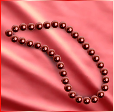珍珠项链在丝绸红色织物上。