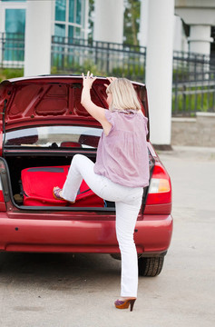 女孩把手提箱裝在汽車行李架上