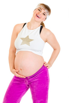 幸福美麗的孕婦穿著運(yùn)動服抱著她的肚子孤立在白色