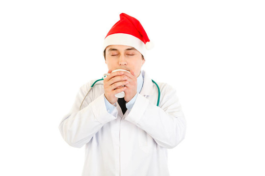 醫(yī)學(xué)博士在Santa的帽子享受白色的熱咖啡杯