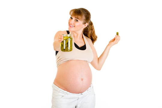 微笑美麗的孕婦手里拿著黃瓜罐子在白色上孤立