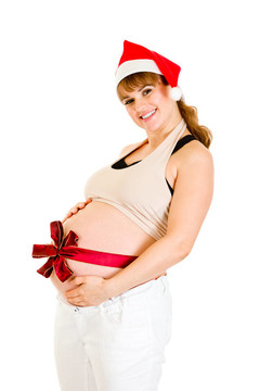 幸福美麗的孕婦在Santa帽子與紅絲帶對(duì)腹部孤立的白色