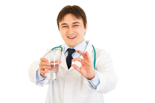 面帶微笑的醫(yī)生用藥片和一杯水在手上用白色隔離