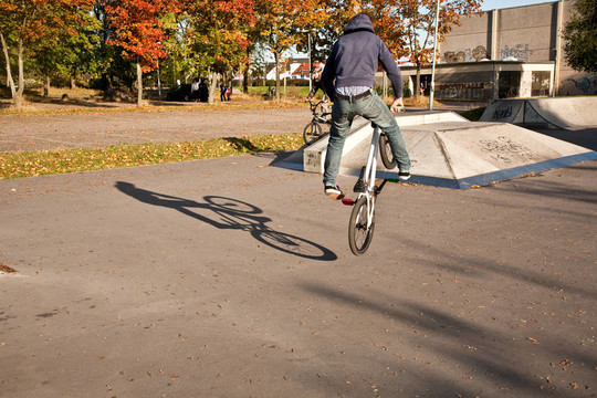 敬紅頭發(fā)的男孩是他的自行車在玩滑板公園跳