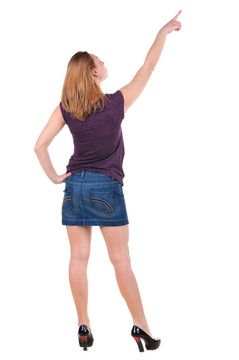 美麗的年輕女子在衣服指著墻壁。后視圖。