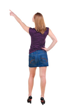 美麗的年輕女子在衣服指著墻壁。后視圖。白色孤立。