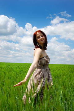 年輕漂亮的女孩在綠色的田野