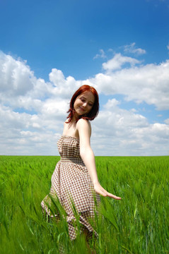 年輕漂亮的女孩在綠色的田野