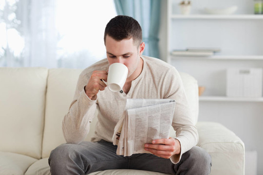 男子一邊喝茶一邊看新聞