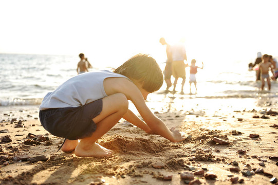 孩子在沙灘上玩沙；周圍的人；夏天熱的好時(shí)光