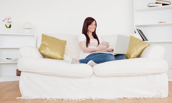 漂亮的女性坐在沙發(fā)上打算在她的公寓里上網(wǎng)