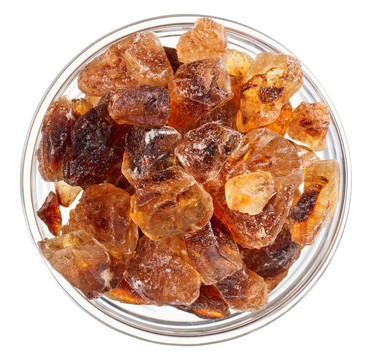 布朗坨蔗糖堆在玻璃碗；孤立的白色