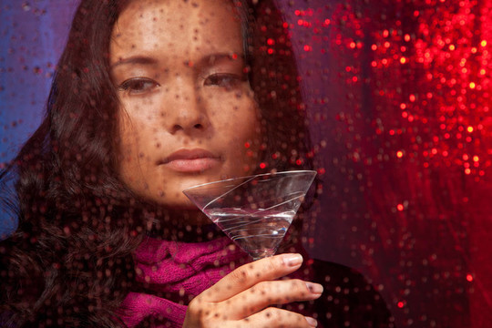 悲傷的亞洲婦女在寒冷的雨天喝