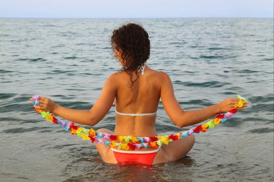 漂亮的年輕女人穿著泳衣抱著海水中花座夏威夷花環(huán)