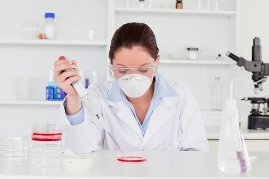 年輕科學家準備一個樣品，同時戴著保護面具