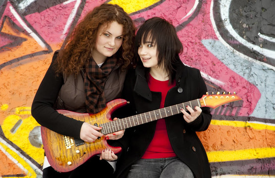 两个风格的青少年女孩在涂鸦背景吉他。