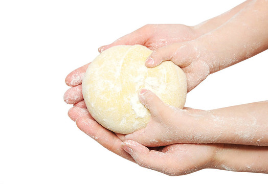 一個(gè)孩子正在幫媽媽揉面團(tuán)做烘焙