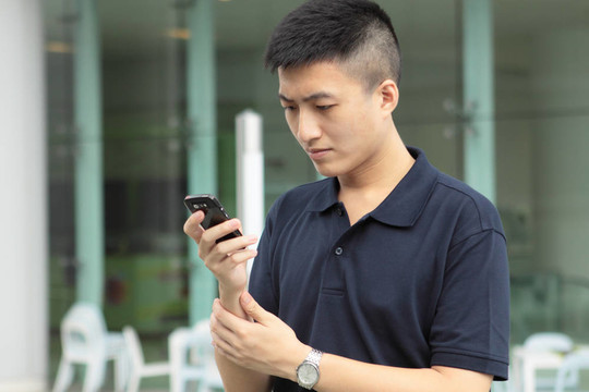 亞洲男子在手機(jī)上輸入信息。