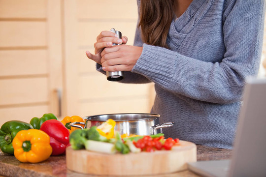 女人在蔬菜燉肉里加胡椒