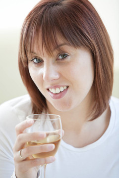 迷人的年輕女子喝了一杯白葡萄酒