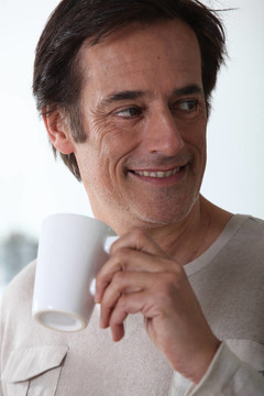 男子笑著喝著一杯茶。