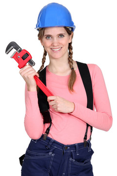 一位女建筑工人拿著扳手。