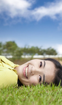 微笑的亞洲年輕女子在草地上