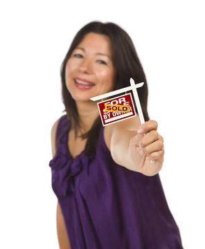 有吸引力的多民族婦女抱著小業(yè)主出售房地產(chǎn)標(biāo)志在手銷售孤立在白色背景。