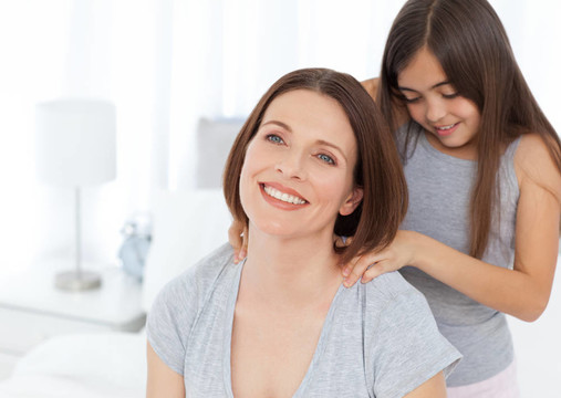 可愛(ài)的女兒梳著她的女人的頭發(fā)