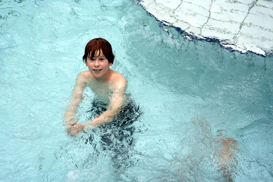 小男孩在公共室内游泳池玩得很开心
