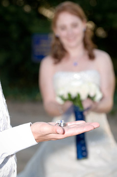 結(jié)婚戒指戴在新郎新娘微笑的棕櫚和背景中手捧鮮花