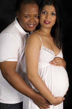 性感美丽怀孕的印度女人和非洲男性拥抱白衣在黑色背景微笑