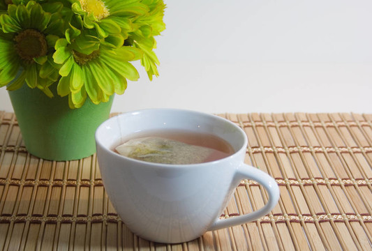 一杯茶在竹子上與綠色的花朵