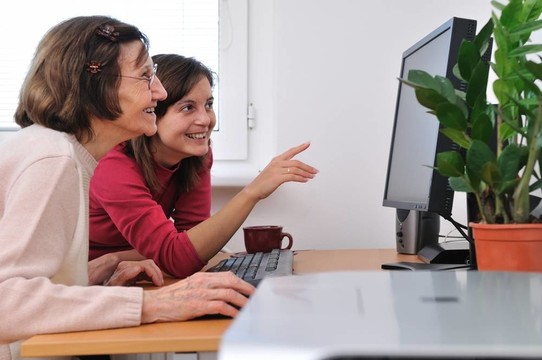 年輕婦女教奶奶用電腦工作