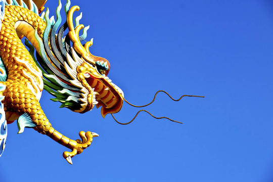 藍(lán)色天空的柱子上的龍雕像