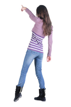 美麗的年輕女子在衣服指著墻壁。后視圖。