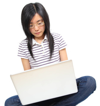 年輕的中國女人坐在地板上用筆記本電腦