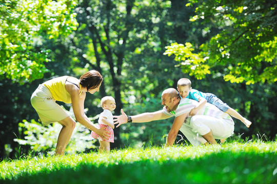 快樂的年輕夫婦和他們的孩子在公園玩得開心