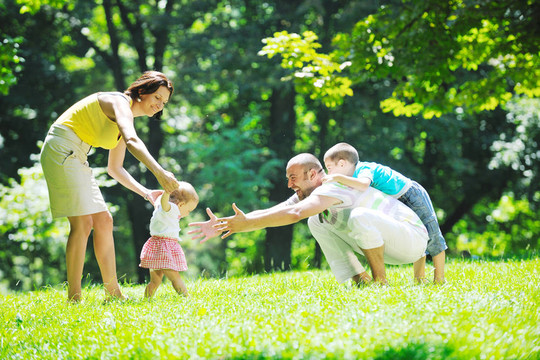 快樂的年輕夫婦和他們的孩子在公園玩得開心